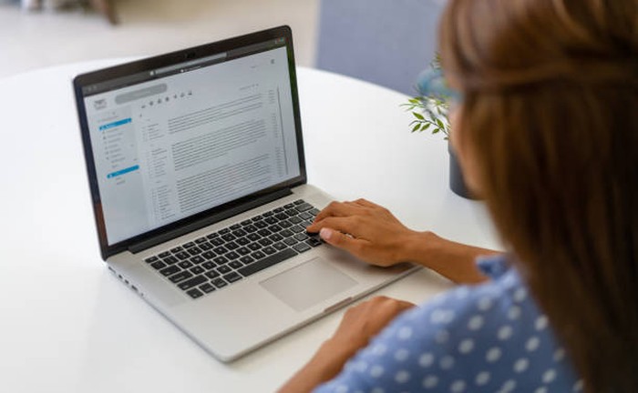 Latin American woman working at home and reading e-mails on her laptop computer - lockdown concepts