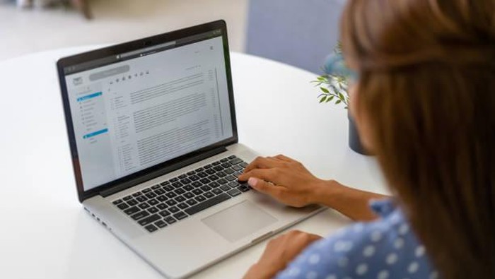 Latin American woman working at home and reading e-mails on her laptop computer - lockdown concepts