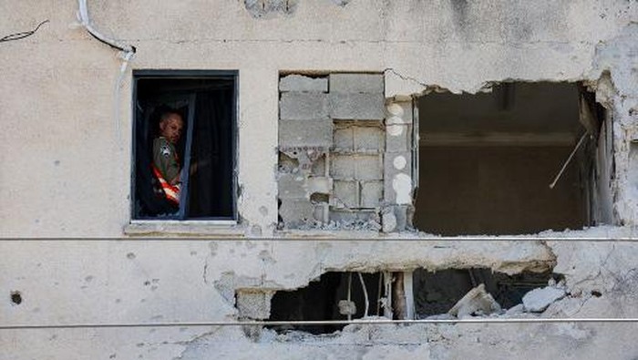 A first responder chacks a building damaged by a rocket fired from Lebanon in Kiryat Ata in Israels Haifa district on October 19, 2024, amid the ongoing war between Israel and Hezbollah. (Photo by Jack GUEZ / AFP)
