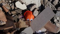 Sebuah maninan anak tertimbun reruntuhan bangunan yang hancur akibat serangan Israel tersebut.  