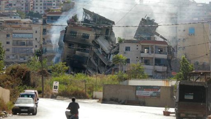 People drive next to a building, targeted in an Israeli airstrike the night before, in Beiruts southern suburbs on October 20, 2024, amid the ongoing war between Hezbollah and Israel. (Photo by Ibrahim AMRO / AFP)