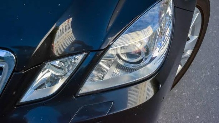 Novosibirsk, Russia - 05.30.2019: Close-up on the hood and fender of the car in black with white dots in the form of chips from stones and rubble that fly off the road. Repair scratches and defects in the body repair workshop.