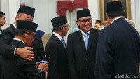 Para menteri laki-laki mengenakan jas hitam dan dasi biru muda.