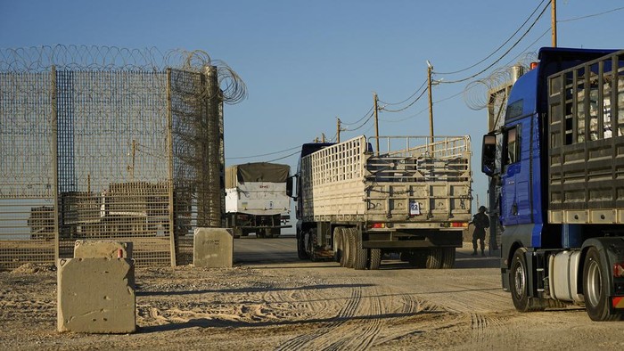 Israeli soldiers stand near trucks carrying humanitarian aid just before they cross into the Gaza Strip at Erez crossing in southern Israel, Monday, Oct. 21, 2024. (AP Photo/Tsafrir Abayov)