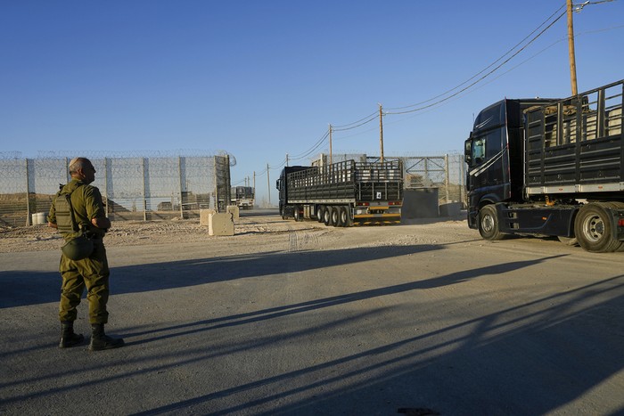 Israeli soldiers stand near trucks carrying humanitarian aid just before they cross into the Gaza Strip at Erez crossing in southern Israel, Monday, Oct. 21, 2024. (AP Photo/Tsafrir Abayov)