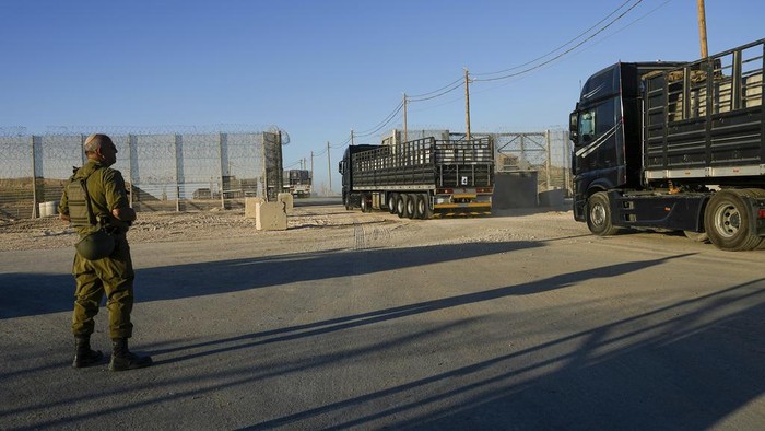Israeli soldiers stand near trucks carrying humanitarian aid just before they cross into the Gaza Strip at Erez crossing in southern Israel, Monday, Oct. 21, 2024. (AP Photo/Tsafrir Abayov)