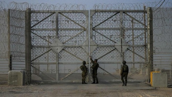 Israeli soldiers stand near trucks carrying humanitarian aid just before they cross into the Gaza Strip at Erez crossing in southern Israel, Monday, Oct. 21, 2024. (AP Photo/Tsafrir Abayov)