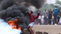 Massa tampak membakar ban dan melemparkan batu ke arah polisi.  