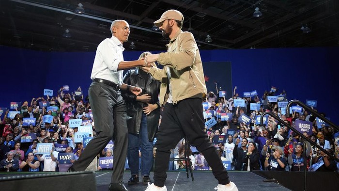 Rapper Eminem, center, greets the crowd on stage with former President Barack Obama, left, at a campaign rally supporting Democratic presidential nominee Vice President Kamala Harris, Tuesday, Oct. 22, 2024, in Detroit. (AP Photo/Paul Sancya)