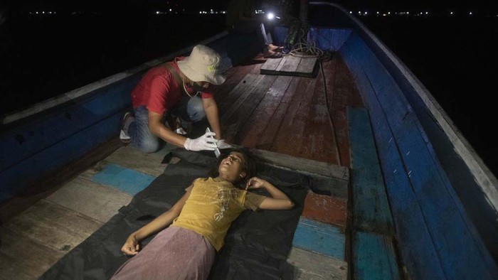 A young Rohingya girl sits on the deck of a refugee boat anchored in the waters near the coast of Labuhan Haji, Aceh province, Indonesia, Tuesday, Oct. 22, 2024. (AP Photo/Binsar Bakkara)