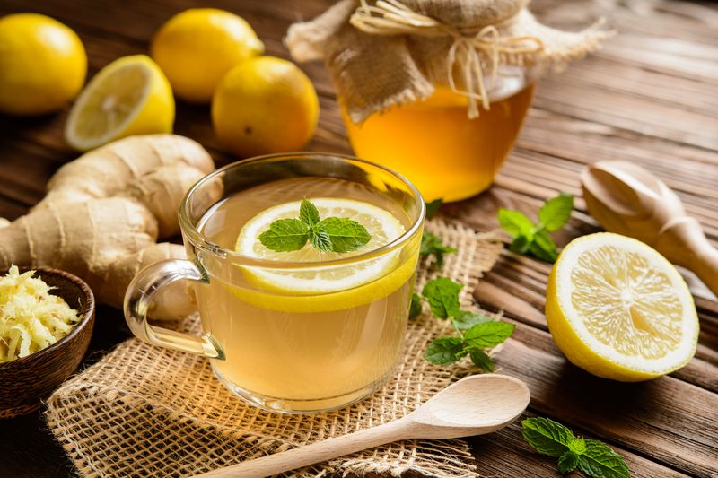 Ilustrasi minuman jahe lemon madu Cup of ginger root tea with lemon, honey and mint on a wooden background