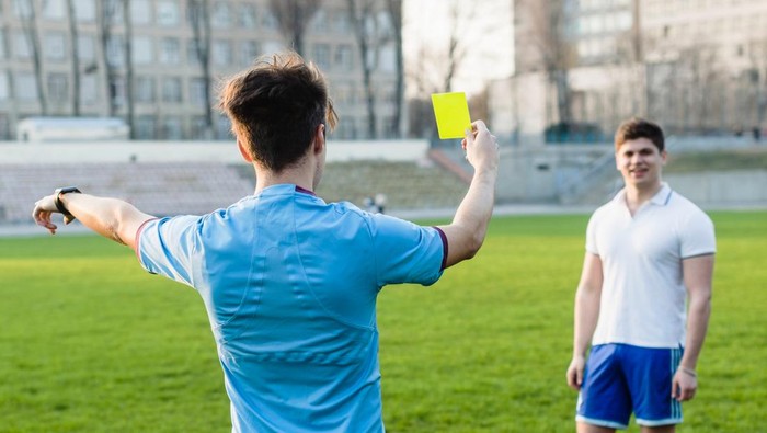 Wasit memberikan kartu kuning kepada pemain dalam pertandingan sepakbola
