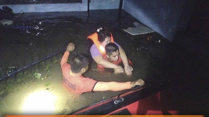 In this photo provided by the Philippine Coast Guard, rescuers carry a resident to safer grounds as they navigate floods caused by Tropical Storm Trami in Guinobatan, Albay province, Philippines Tuesday Oct. 22, 2024. (Philippine Coast Guard via AP)