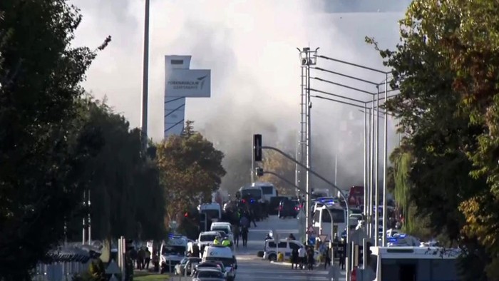 Smoke raises as emergency rescue teams and police officers attend outside Turkish Aerospace Industries Inc. on the outskirts of Ankara, Turkey, Wednesday, Oct. 23, 2024. (IHA via AP)