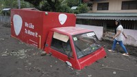 Seorang warga berjalan di samping truk yang terkubur material vulkanik yang mengalir dari gunung berapi Mayon setelah hujan lebat akibat Badai Tropis Trami melanda kota Guinobatan, provinsi Albay, Filipina, Rabu (23/10/2024).