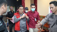 Ketiga tampak diborgol dan memakai rompi tahanan.