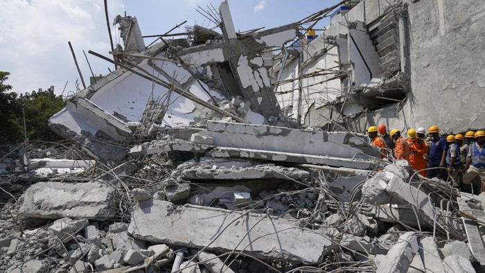Rescue workers remove the debris to look for the trapped survivors of an under-construction building that collapsed on Tuesday, following heavy rains in Bengaluru, India, Wednesday, Oct. 23, 2024. (AP Photo/Aijaz Rahi)