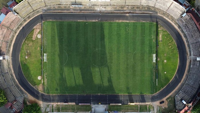Foto udara pekerja memotong rumput lapangan stadion GOR H Agus Salim Padang, Sumatera Barat, Kamis (24/10/2024). Stadion yang direnovasi itu kini sudah bisa digunakan untuk pertandingan Liga 1 sebagai markas tim Semen Padang FC.  ANTARA FOTO/Iggoy el Fitra/YU