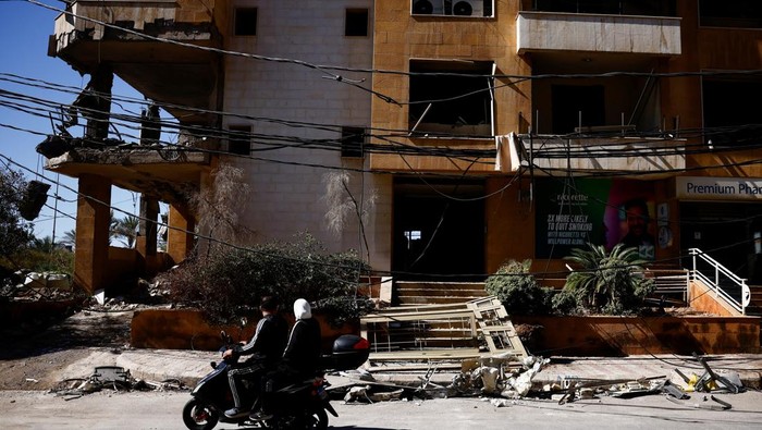 People sit on mopeds near the site of an Israeli strike that destroyed an office used by the pro-Iran Al-Mayadeen broadcaster, amid ongoing hostilities between Hezbollah and Israeli forces, in Beirut suburbs, Lebanon October 24, 2024. REUTERS/Yara Nardi