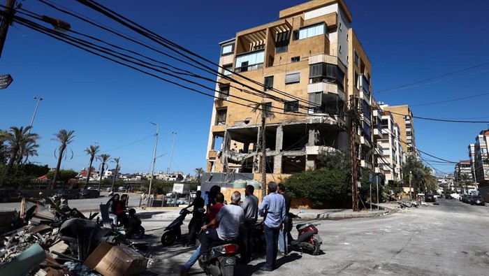 People sit on mopeds near the site of an Israeli strike that destroyed an office used by the pro-Iran Al-Mayadeen broadcaster, amid ongoing hostilities between Hezbollah and Israeli forces, in Beirut suburbs, Lebanon October 24, 2024. REUTERS/Yara Nardi