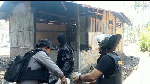 Polisi tengah menyiram rumah warga yang masih ada nyala api di Desa Bugalima, Senin (21/10/2024).