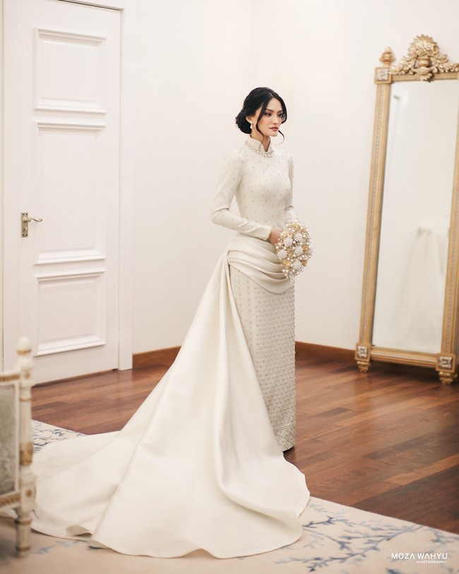 Sejak awal prosesi, wanita 29 tahun tersebut sudah mengenakan busana rancangan desainer lokal untuk hari bahagia. Untuk akad, Tengku Natasya terlihat menawan dengan gaun maksi putih dari Hian Tjen.  Foto: Instagram @mozawahyu