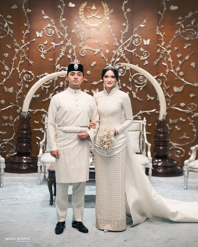 Tengku Nastasya Adnan semakin cantik mengenakan tiara yang melengkapi penampilan princess-nya. Ia juga menerapkan makeup flawless dengan aksentuasi pulasan lipstik merah. Sang pengantin pun menambahkan aksesori bernuansa silver dan high heels putih yang senada dengan gaun pernikahannya. Foto: Instagram @mozawahyu