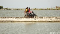 Warga melintas di daratan yang tersisa di Desa Legonwetan, Kecamatan Legonkulon.  Abrasi dari Laut Jawa menggerus tanah mereka.