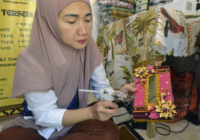 Perajin menyelesaikan produksi suvenir khas Lampung di Durian Payung, Bandar Lampung, Lampung, Sabtu (26/10/2024).  Perajin menyebutkan dalam sebulan mampu menjual sedikitnya 100 buah suvenir hias bermotif tapis khas Lampung, seperti tutup gelas, topi tapis, kotak tisu, gantungan kunci serta dompet ke berbagai kota di Indonesia secara daring maupun luring dengan harga Rp10 ribu hingga Rp300 ribu rupiah per buah tergantung bahan dan tingkat kesulitan pembuatannya. ANTARA FOTO/Ardiansyah/nz.