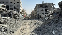 Seorang pria Palestina berjalan melewati reruntuhan bangunan yang disebabkan serangan setelah pasukan Israel di sekitar rumah sakit Kamal Adwan.