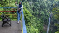 Wisatawan berfoto dengan latar belakang Curug Pelangi Cimahi di Cisarua, Kabupaten Bandung Barat, Jawa Barat, Minggu (27/10/2024).