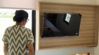 Bunda Corla menunjukkan contoh kamar kalau rumahnya sudah jadi. Ruangan ini memiliki jendela yang lebar dan wall panel kayu untuk memasang TV di dinding. Interior kamarnya terlihat minimalis dengan nuansa putih dan abu-abu.