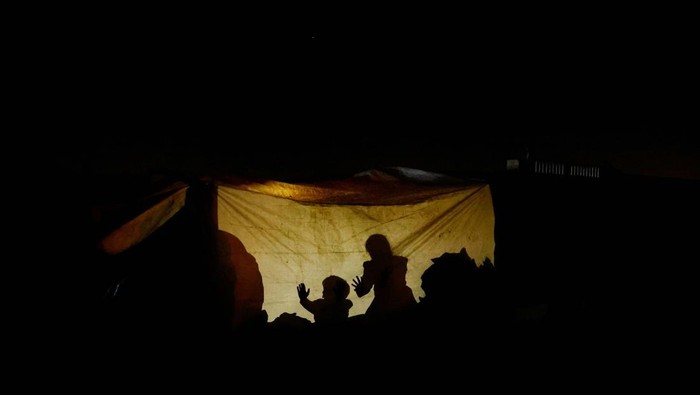 Displaced Palestinian light a fire at their tent as they live at a cemetery, amid the Israel-Hamas conflict, in Khan Younis, in the southern Gaza Strip, October 27, 2024. REUTERS/Mohammed Salem