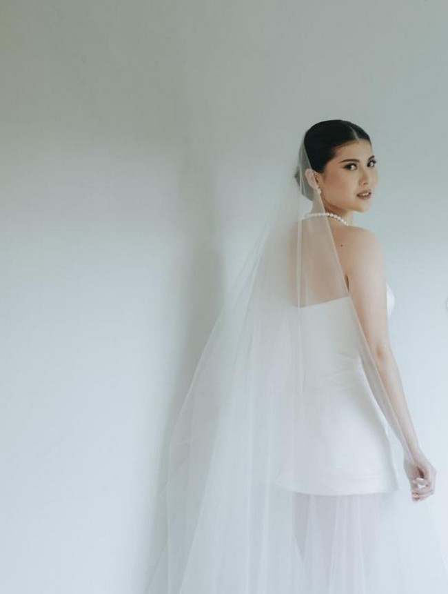 Wanita 28 tahun ini memilih gaun putih dengan aksen pita rancangan desainer bridal Elsie Chrysila. Untuk makeup, dia mempercayakan kepada penata rias Vanny Adelina. Foto: Instagram/@vanny.adelina @morden.co