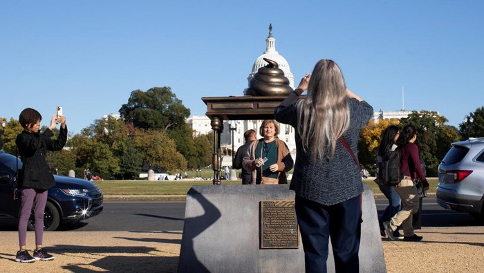 Patung Kotoran Muncul di Depan Gedung DPR AS A new temporary statue of a brass-colored desk with a large poop-shaped emoji on top of it, referencing those who attacked the U.S. Capitol on January 6, 2021, is seen near the Capitol in Washington, U.S., October 25, 2024. REUTERS/Kaylee Greenlee Beal
