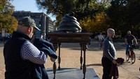 Sebuah tanda di bawah meja menunjukkan tujuannya: Tugu peringatan ini menghormati para pria dan wanita pemberani yang menerobos Gedung DPR Amerika Serikat pada tanggal 6 Januari 2021 untuk menjarah, buang air kecil, dan buang air besar di seluruh aula suci itu untuk membatalkan pemilu. Presiden Trump merayakan para pahlawan 6 Januari ini sebagai patriot yang luar biasa dan pejuang. Monumen ini berdiri sebagai bukti pengorbanan mereka yang berani dan warisan yang abadi, kata tanda itu.  