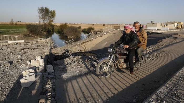 A Syrian boy fleeing the war in Lebanon carries his luggages as he passes through a crater caused by an Israeli airstrike, which blocks the road between the Lebanese and the Syrian crossing points, in Jousieh, Syria, Sunday, Oct. 27, 2024. (AP Photo/Omar Sanadiki)
