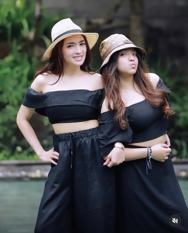 Seperti dalam foto, Angel dan Lovely tampil ‘kembar’ dalam balutan crop top sabrina dan rok panjang berwarna hitam. Penampilan keduanya juga dilengkapi dengan bucket hat berwarna coklat. Foto: Instagram/@realangelkaramoy