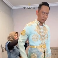 Atasan busana pengantin yang berwarna biru muda itu tampak memiliki ukiran berwarna emas. Atasan lengan panjang tersebut dipadukan dengan kain berwarna hijau dan kuning. Foto: Instagram/@barry_irawan/@whulyan