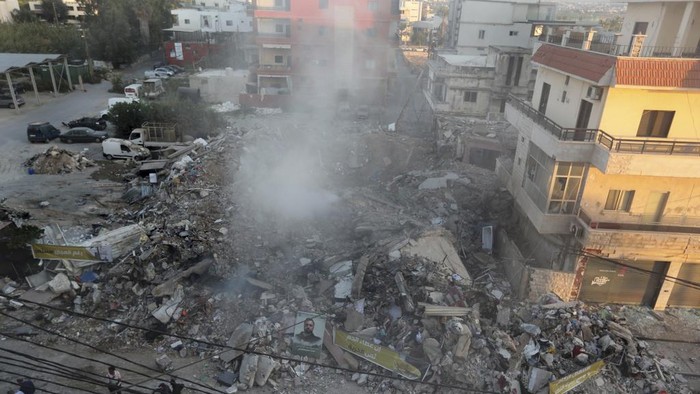 Journalists film as smoke rises from buildings hit in Israeli airstrikes in Tyre, southern Lebanon, Monday, Oct. 28, 2024.(AP Photo/Mohammed Zaatari)