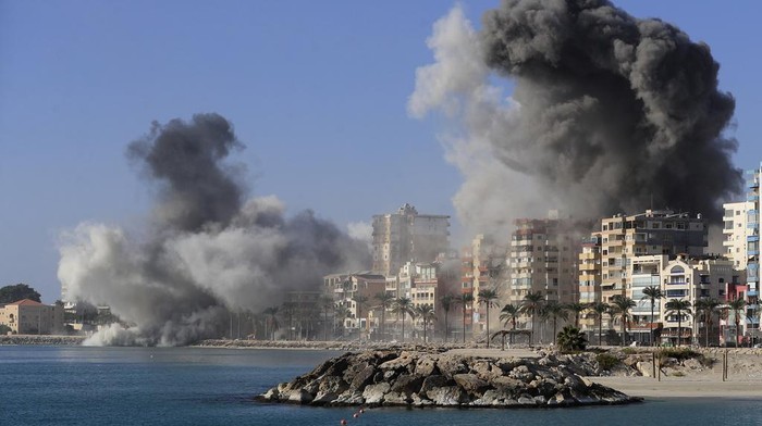 Journalists film as smoke rises from buildings hit in Israeli airstrikes in Tyre, southern Lebanon, Monday, Oct. 28, 2024.(AP Photo/Mohammed Zaatari)