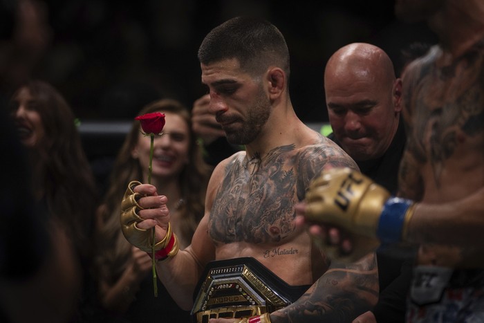 UFC featherweight champion Ilia Topuria, holds a rose presented to him by his wife after winning the featherweight title mixed martial arts bout against No. 2 ranked Max Holloway at UFC Fight Night on Saturday, Oct. 26, 2024, in Abu Dhabi, United Arab Emirates. Topuria won the fight. (AP Photo/Altaf Qadri)