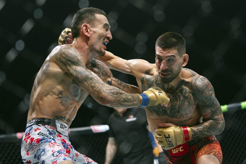 UFC featherweight champion Ilia Topuria, holds a rose presented to him by his wife after winning the featherweight title mixed martial arts bout against No. 2 ranked Max Holloway at UFC Fight Night on Saturday, Oct. 26, 2024, in Abu Dhabi, United Arab Emirates. Topuria won the fight. (AP Photo/Altaf Qadri)