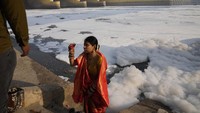 Seorang wanita dengan pakaian tradisional difoto di depan sungai Yamuna yang dipenuhi busa beracun di New Delhi, India, Selasa (29/10/2024). Yamuna merupakan salah satu sungai paling suci di India, telah ditutupi busa putih beracun yang sebagian besar akibat polutan yang dibuang dari industri di sekitar kota. Polusi tersebut menimbulkan ancaman kesehatan serius bagi penduduk karena sungai tersebut menyediakan lebih dari separuh air ibu kota India.