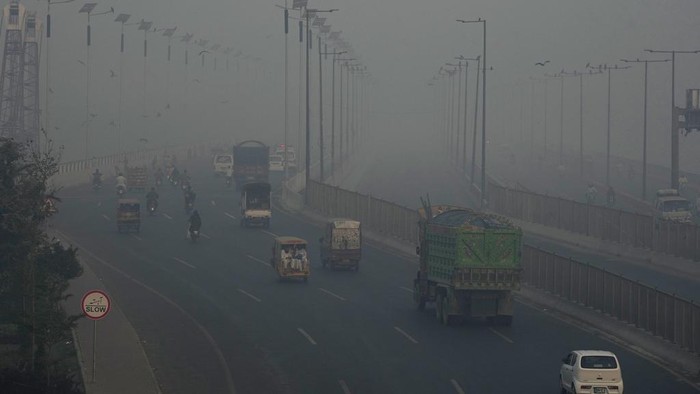 Vehicles move slow on a road as smog envelops the area, in Lahore, Pakistan, Monday, Oct. 28, 2024. (AP Photo/K.M. Chaudary)