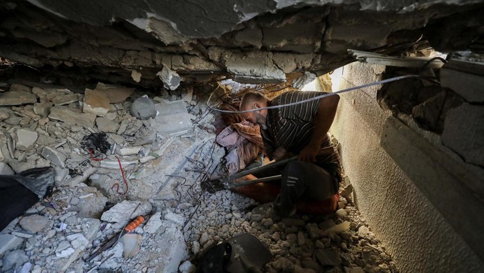 Sekolah Hancur Dibom Israel, Anak-anak Tertimbun Reruntuhan Bangunan A man works to recover the body of a Palestinian child trapped under the rubble of a building in a school-turned-shelter hit in an Israeli strike on Sunday, amid the ongoing Israel-Hamas conflict, at Beach camp in Gaza City, October 28, 2024. REUTERS/Dawoud Abu Alkas