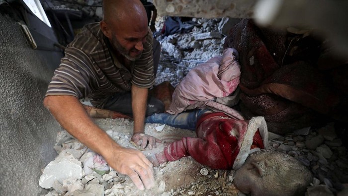 A man works to recover the body of a Palestinian child trapped under the rubble of a building in a school-turned-shelter hit in an Israeli strike on Sunday, amid the ongoing Israel-Hamas conflict, at Beach camp in Gaza City, October 28, 2024. REUTERS/Dawoud Abu Alkas