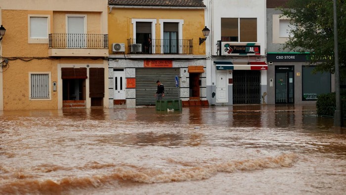 A person walks in a flooded street after the Spanish meteorological agency put the Valencia region in the highest red alert for extreme rainfalls, in Llombai, Valencia, Spain, October 29, 2024. REUTERS/Eva Manez