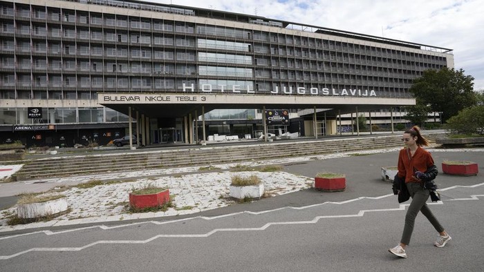 Hotel Yugoslavia yang Dulunya Favorit Bangsawan Kini Terbengkalai A woman walks past Hotel Yugoslavia, once a symbol of progress in the former socialist state of Yugoslavia that broke apart in the 1990s and a favorite gathering place for local residents as well as world leaders, in Belgrade, Serbia, Thursday, Oct. 3, 2024. (AP Photo/Darko Vojinovic)