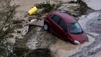 Sebuah mobil nyangkut di tanggul usai terseret aliran banjir.